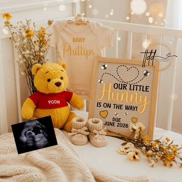 Baby reveal setup with teddy bear, baby onesie, and pregnancy announcement sign.